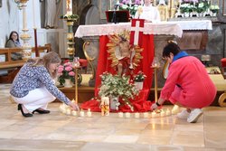 Zwei Mitglieder des Frauenbundes Gündlkofen entzünden vor dem Altar Kerzen.